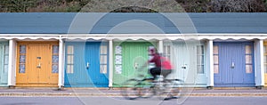 Bournemouth UK. People cycling in front of colourful beach huts located on the promenade on the Bournemouth sea front.