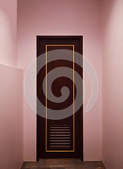 Boutique vintage retro wooden door made from plain tropical dark brown textured wood panel board with pink color painted wall back