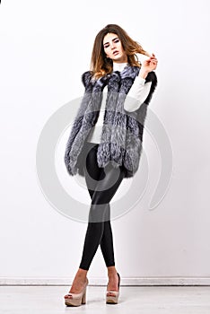 Boutiques selling fur. Woman makeup face wear fur vest white background. Luxury fur accessory clothes. Fashion trend photo