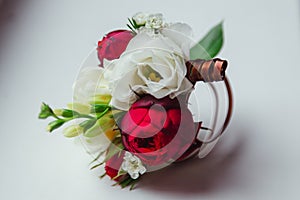 Boutonniere made of dark rose and white flower lies on the table