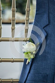 BoutonniÃÂ¨re on grooms jacket hanging over a chair at wedding reception photo