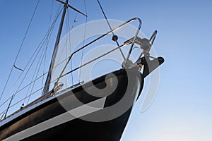 Bow of a black sailing yacht from below against the blue sky, co