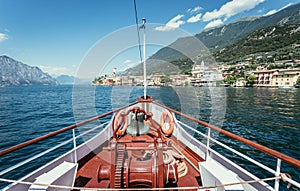 Boat tour: Boat bow, view over azure blue water, village and mountain range. Lago di Garda, Italy photo