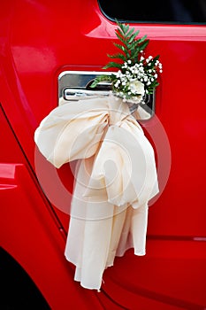 Bow with flowers on door handle of wedding limo
