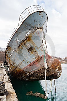 Bow of an old abandoned ship hangs over the sea