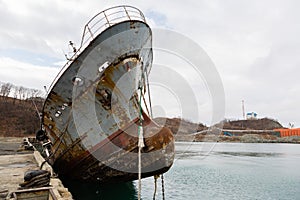 Bow of an old abandoned ship hangs over the sea