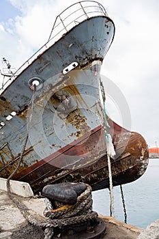 Bow of an old abandoned ship hangs over the sea