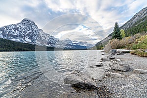 Bow river in Banff National park with snow cap mountains ranges under cloudy blue sky,