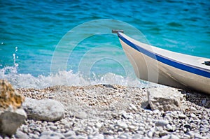 Bow small boat sea waves crashing shore pebble beach