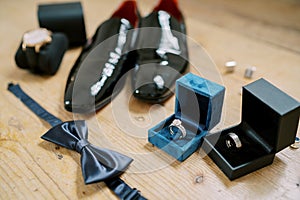 Bow tie lies on the floor near boxes with wedding rings and men shoes