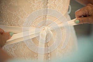 a bow is tied on the back of a brides dress for wedding preparation