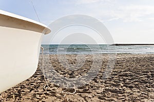 Bow of a white boat aground on Cubelles beach in the Mediterranean Sea in a sunny day of summer. Barcelona, Spain