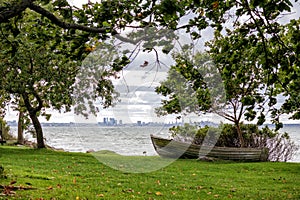 The bow of a wooden boat on the shore against the background of the city and the sea