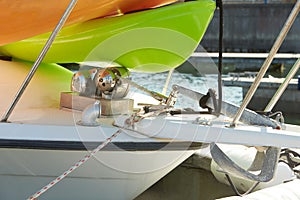 The bow of the yacht with anchor stops, a winch, a bollard with a mooring rope fixed to it and part of the anchor chain.