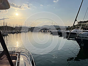 bow of a yacht entering a marina with the soft hues of the setting sun in the sky