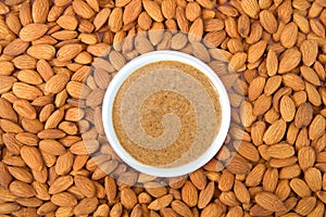 Bowl of almond butter surrounded by raw fresh almonds