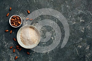 Bowl of almond flour and bowl of almonds from top view, copy space.