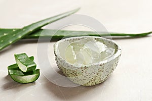 Bowl with aloe vera gel and fresh leaves