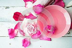 Bowl of aroma spa water with rose petals on towel, closeup