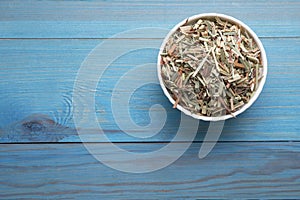 Bowl with aromatic dried lemongrass on light blue wooden table, top view. Space for text