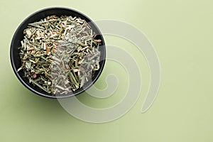 Bowl with aromatic dried lemongrass on light green background, top view. Space for text