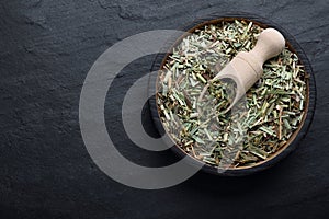 Bowl with aromatic dried lemongrass and scoop on black table, top view. Space for text