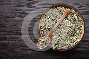 Bowl with aromatic dried lemongrass and spoon on wooden table, top view. Space for text