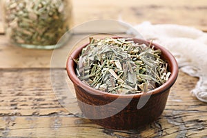 Bowl with aromatic dried lemongrass on wooden table, closeup