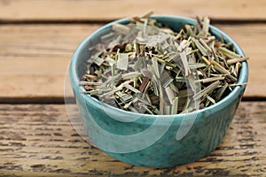 Bowl with aromatic dried lemongrass on wooden table, closeup