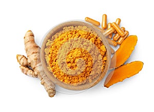 Bowl of aromatic turmeric powder, pills and raw roots isolated on white, top view