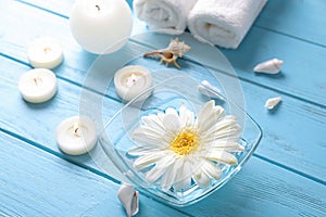 Bowl with aromatic water and candles on wooden table in spa salon
