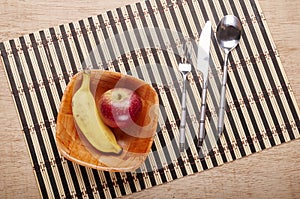 Bowl with banana and strawberry and cutlery on the table