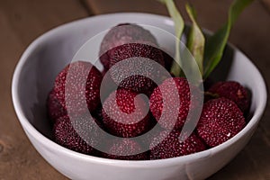 A bowl of bayberry fruit on a wooden plank