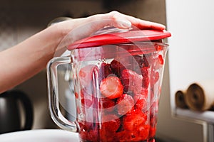 Bowl of blender filled with strawberries