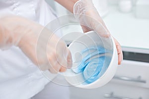 bowl with blue alginate mask in hands of beautician.