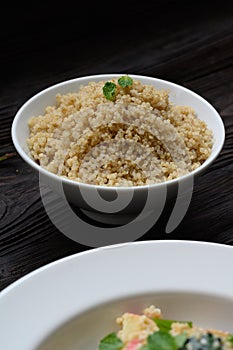 Bowl of boiled quinoa on wood background