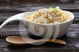 Bowl of boiled quinoa on wood background