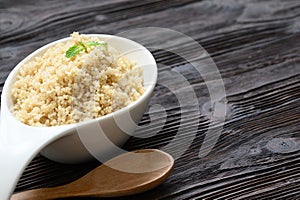 Bowl of boiled quinoa on wood background