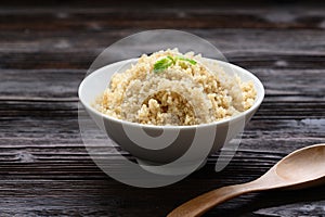 Bowl of boiled quinoa on wood background