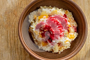 Bowl with boiled rice cooked in milk with sultana, pieces of pumpkin and flavoured with fresh raspberry juice