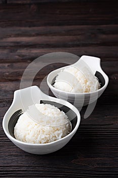 Bowl of boiled rice served on wooden table