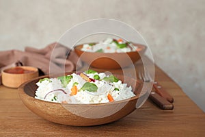 Bowl of boiled rice with vegetables on table.