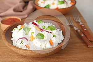 Bowl of boiled rice with vegetables on table.