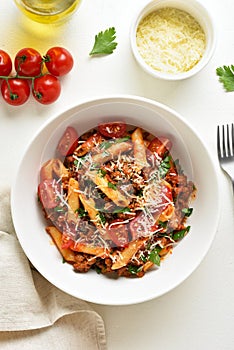 Bowl of bolognese penne pasta with minced meat, tomatoes and gre