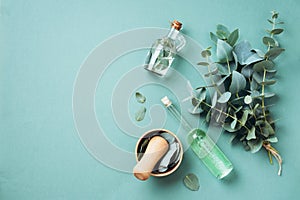 Bowl, bottles of eucalyptus essential oil, mortar, bunch of fresh eucalyptus branches on green background. Natual organic