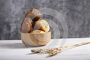 A bowl of bread and and ears of wheat isolated against grey background