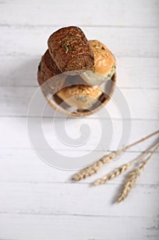 A bowl of bread and and ears of wheat isolated against wooden background flat lay