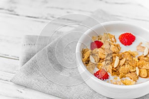 Bowl of breakfast cereals with milk and strawberries.