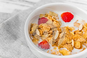 Bowl of breakfast cereals with milk and strawberries.
