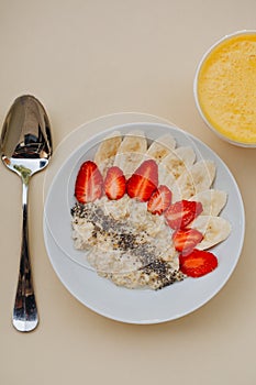 Bowl of breakfast muesli decorated with banana, strawberry slices and chia seed, top view